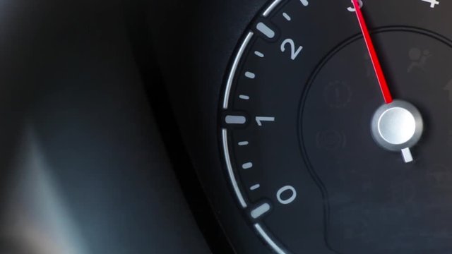 Color close up footage of a car's tachometer revving.