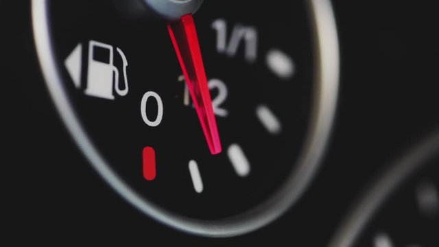 Color close up footage of a car's fuel gauge with the needle moving.