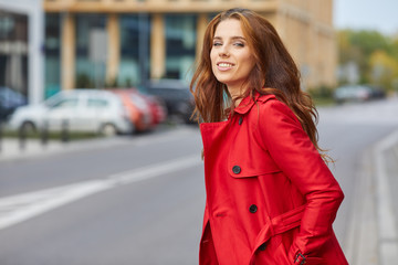 Fototapeta premium Beautiful stylish woman in a red coat. The city in the backgroun