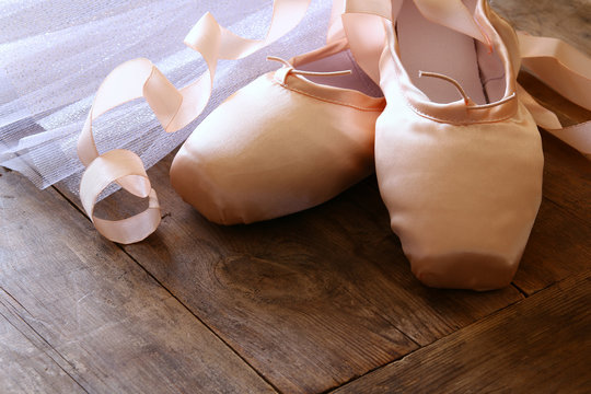 Image of silk pointe shoes and tutu on wooden floor