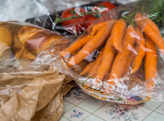 Brötchen, Tomaten und Karotten mit Plastik verpackt