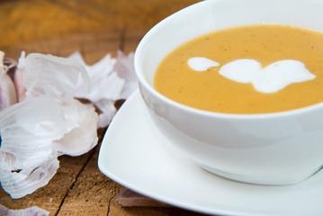 Garlic cream soup in orange bowl on wooden background. rustic country style.