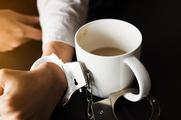 handcuffs with with cup of coffee.
maniac caffeine addiction concept.
shallow depth of field.