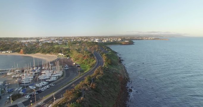 Drone flight in straight line over Mornington monument along the coastline towards suburban area.  Mornington Peninsula, Victoria, Australia.