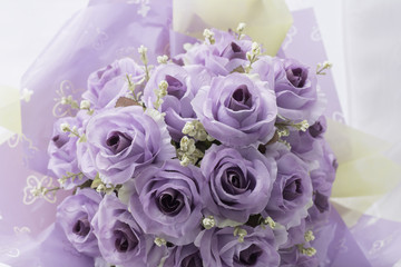Artificial purple roses on a white background.