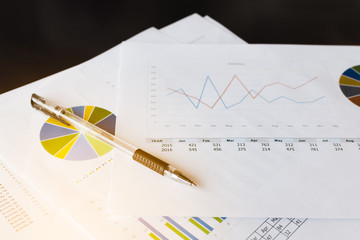 close up of pen with work paper on desk . 
expression of feeling in worker concept.
shallow depth of field,sunshine effect. 