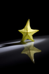 Slice of star fruit on a black background with a beautiful back light.