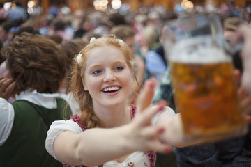 Excited girl reaches for a mug of beer at Oktoberfest