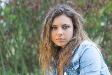 Portrait of long hair brunette teenage girl outdoors. Girl is looking at the camera. 