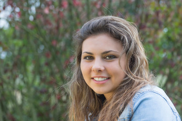 Portrait of smiling long hair teenage girl in outdoors. Girl is looking at the camera. 