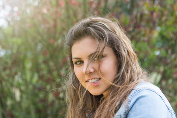 Portrait of attractive long hair teenage girl with head cocked biting her lips. Girl is looking at the camera. 