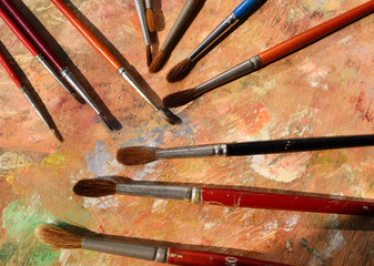 Many old paint brushes on a dirty palette