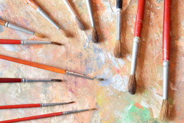Many old paint brushes on a dirty palette