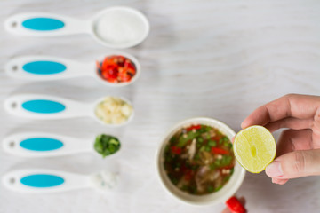 Close up woman hand cooking seafood sauce, spicy sauce of seafood , favorite Sauce in Thailand,Cooking sauce for seafood, white wooden background. Hand mixing tasty gravy in pan on table.