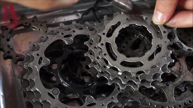 Hand of a mechanic cleaning a bicycle gear cassette / Bicycle maintenance concept
