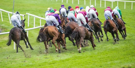 Crédence de cuisine en verre imprimé Léquitation chevaux de course et jockeys tournant le coin de la piste pendant une course