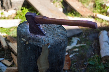 Large ax stuck in a tree stump while chopping wood.