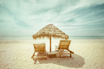 Fototapeta premium Amazing tropical beach landscape with thatch umbrella and chairs for relaxation on sand. Travel background in vintage style