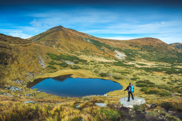 Fototapeta na wymiar Hiker with backpack and trekking poles on a lake