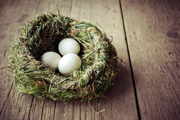 Organic white eggs in hay nest at wooden table. Eco food composition in rural vintage style