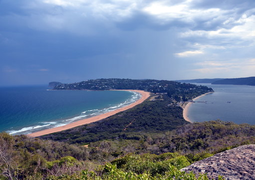 Palm Beach one of Sydney's iconic northern beaches. Barrenjoey lighthouse, dividing Pittwater from Tasman Sea, Sydney, NSW, Australia. Coast headland panorama with bay and surrounding green mountains.