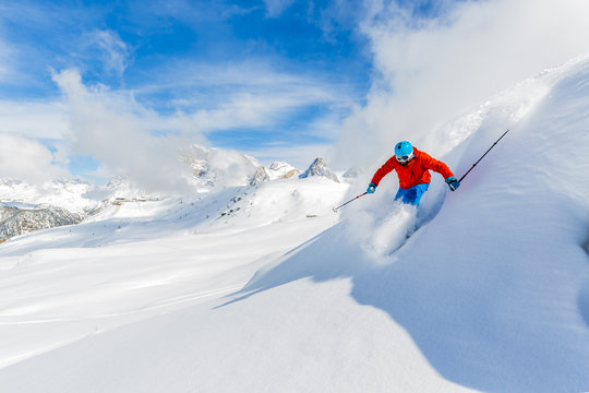 Skier skiing downhill in high mountains in fresh powder snow. 