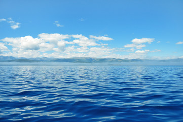 sea lanscape. blue sky, clouds over the surface of sea. mountain on horizon