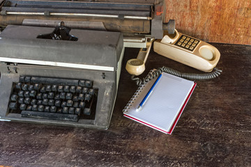 Vintage typewriter ,white book, ,pencil and old telephone on old wooden touch-up in still life concept