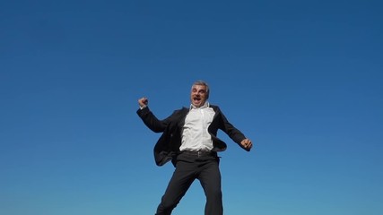 happy excited businessman jumping into blue sky celebrating arms outstretched slow motion - Powered by Adobe