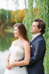 Fototapeta premium Young smiling bride and groom close portrait in summer park