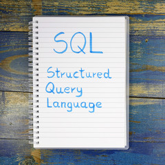 SQL - Structured Query Language written in notebook on wooden background