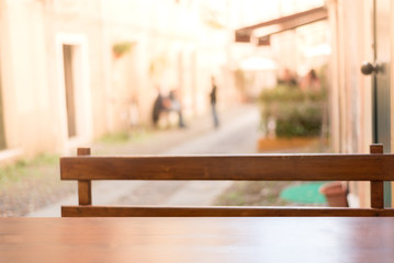 Empty wooden table in the restaurant garden, small Italian street in Alghero town, Sardinia, Italy