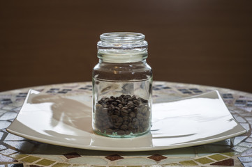 ziarnista kawa w szklanym słoiku na białym talerzyku, coffee beans in a glass jar