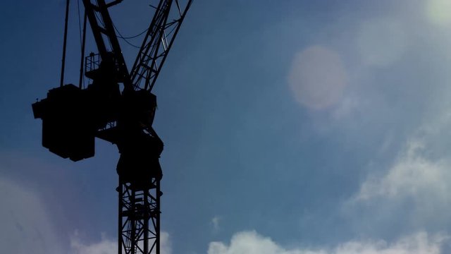 Time lapse of clouds rolling past an industrial crane during the daytime