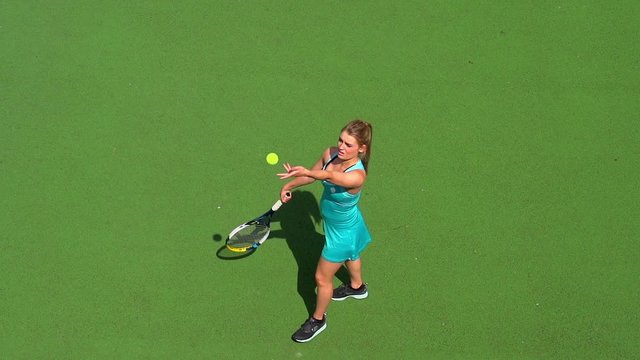 Young female tennis player serves.