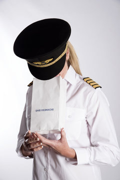 Woman using a sickness bag - September 2016 - A uniformed female pilot feeling nauseous using a paper sickness bag