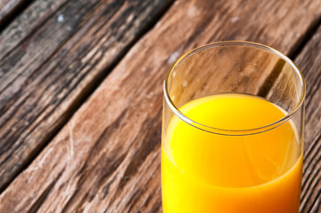 Glass of orange juice on wooden background. Copyspace