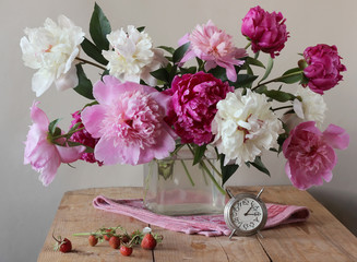 Still-life with a bouquet of peonies and strawberries.
