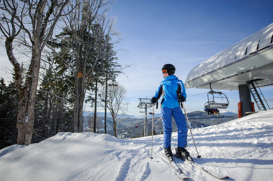 Full length portrait of female skier on the top of ski slope with ski lift and mountains on the background. Winter sports concept. Carpathian Mountains, Bukovel, Ukraine