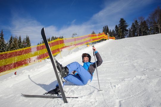 Young woman skier in blue ski suit after the fall on mountain slope. Sunny day. Ski resort. Winter sports concept. Carpathian Mountains, Bukovel