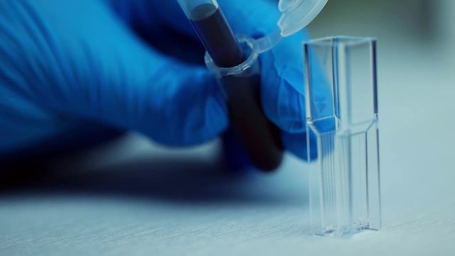 Sample filling in spectrophotometer cuvettes for analysis, close up. Slow motion.