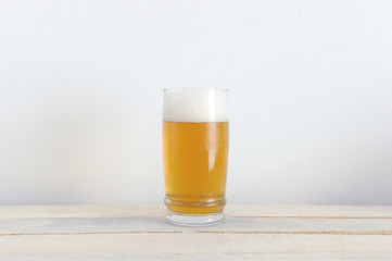 A glass of chilled beer on a white wooden table. White background and empty copy space for Editor's text.