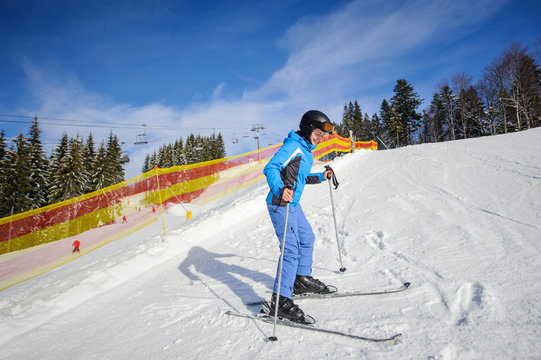 Happy young female skier learning to ski on a sunny day at ski resort with ski-lift and mountains on the background. Winter sports concept. Carpathian Mountains, Bukovel, Ukraine