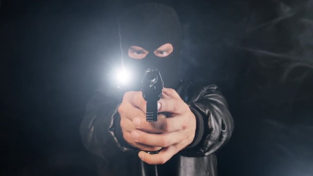 gangster appears in the dark pointing pistol gun to the camera