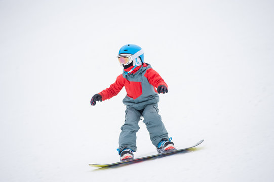 Snowboarder boy riding over the slope at the mountains overlooking the white snowy slope at a winter resort, extreme sport. Close-up