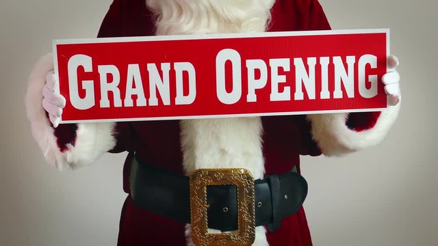 Santa Claus Holds Up A Grand Opening Sign