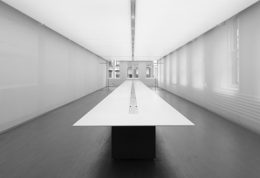 Diminishing perspective of dining table in empty room, black and white image