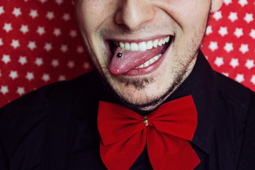 Hombre joven hipster  sacando la lengua y enseñando su piercing 
