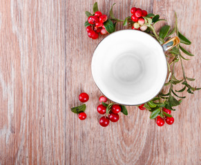 red lingonberries and empty coffee cup on wooden background