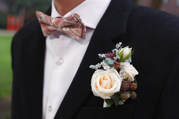 Ivory roses and blackberries boutonniere on black suit of the groom